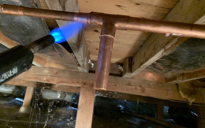 Plumber soldering a copper water line tee during a Sacramento commercial kitchen repair